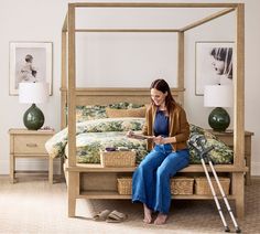 a woman sitting on top of a wooden bed