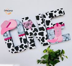 the letters are made out of paper and decorated with cow print, pink cowboy boots, and a hat