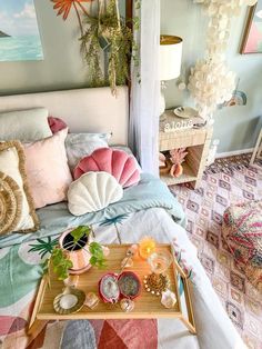 a bed with colorful pillows on top of it next to a tray filled with food