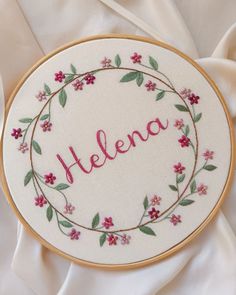 embroidered name on white fabric with pink flowers and green leaves around the word'helen '