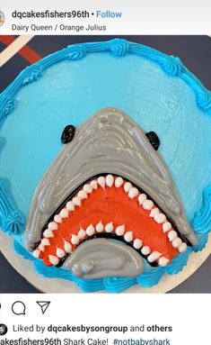 a shark cake is decorated with blue icing and white frosting on the top