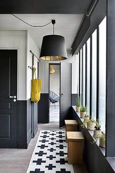 a hallway with black and white checkered flooring, hanging lights and potted plants