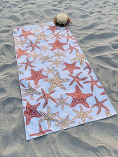 a beach towel with starfishs on it laying in the sand