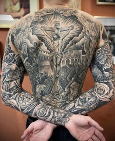 the back of a man with tattoos on his body and hands in front of him