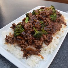 a white plate topped with meat and broccoli covered in sauce on top of rice