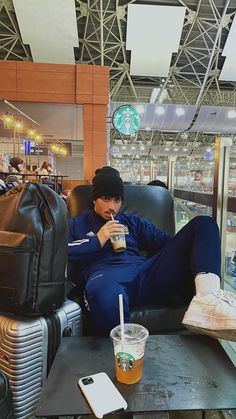 a man sitting in a chair drinking from a cup