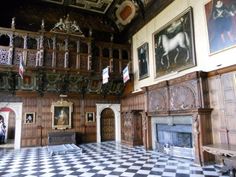 an ornate room with paintings on the walls and a checkered floor in front of a fireplace