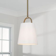 a white light hanging from a ceiling fixture in a room with windows and a rug on the floor