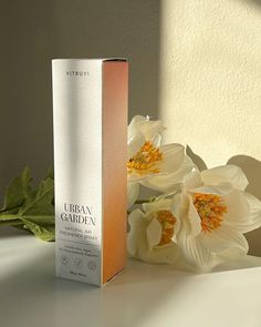 a white box sitting on top of a table next to flowers