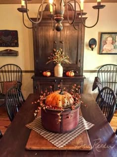 a wooden table topped with a potted pumpkin on top of a wooden dining room table