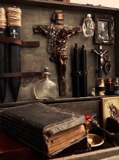 an old book and other items are on a table in front of a crucifix