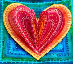 a heart shaped paper cut out on top of a blue and green plate with an intricate design