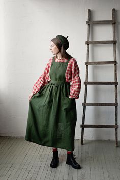 Long cross back pinafore is made from 100% soft and washed linen.  Details: - Colour: Forest green - Composition: 100% Oeko-Tex certified linen - Cross back - Adjustable with buttons - Size: One size - Medium weight linen - Linen care: machine wash gentle; tumble dry low, ironing optional - The price is for one pinafore dress, other pictured items are not included The model is 173 cm/5'8" and wears a size one size. Olive Pinafore Dress, Cottagecore Pinafore Dress, Ora Pinafore, Cotton Knee-length Pinafore Dress With Pockets, Linen Apron Pinafore, Linen Pinafore, Apron Cooking, Apron For Women, Pinafore Apron