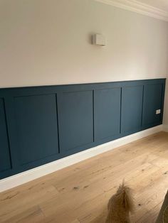 an empty room with wood floors and blue paneling