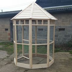 a small wooden structure with a chicken in it's cage on the ground next to a brick building