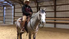 a man riding on the back of a white horse in an indoor arena at night