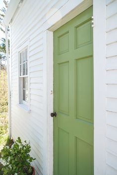 a white house with a green door and potted plants