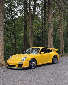 a yellow sports car parked in front of some trees