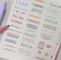 a notebook with some stickers on it next to a pink pen and two pens