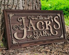 a wooden sign that says jack's bar next to a tree