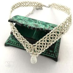 a green and silver necklace with a crystal drop