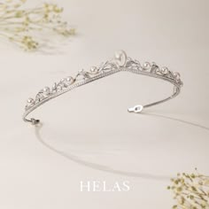 a tiara with pearls is shown on a white surface and flowers are in the background