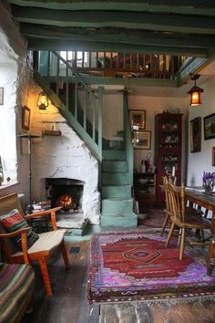 a living room filled with furniture and a fire place under a stair case on top of a wooden floor