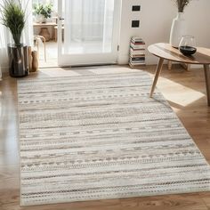 a living room area with a rug, coffee table and potted plant