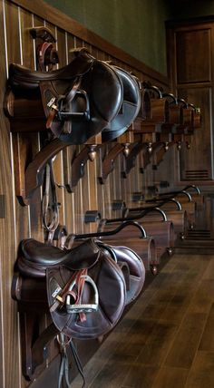 the horse saddles are lined up on the wall