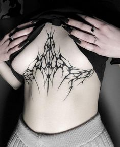 a woman's lower back tattoo with branches on her body and hands behind her