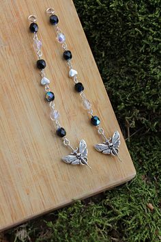 a pair of black and white beaded necklaces on a wooden board next to green grass