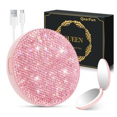 an open round mirror next to a pink case and plugged charger with the box