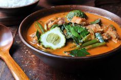 a bowl filled with soup and vegetables on top of a wooden table