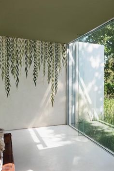 an indoor room with glass walls and plants on the wall, along with a bench