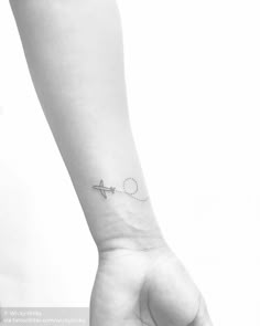 a small airplane tattoo on the left inner arm, with an arrow in the middle