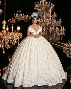 a woman in a ball gown standing next to a chandelier filled with lights