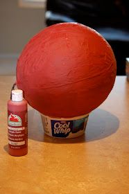 a red ball sitting on top of a wooden table next to a bottle of glue