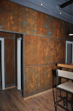 an empty room with some chairs and a table in front of the wall that has been painted gold