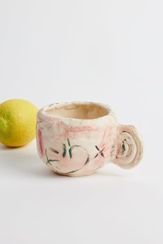 a ceramic cup and lemon sitting next to each other