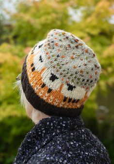 the back of a person wearing a knitted hat with orange and black stars on it