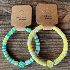 two bracelets with lemon slices on them sitting on top of a wooden table next to each other