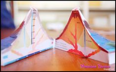 two origami paper boats sitting on top of a wooden table next to each other