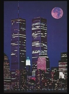 two tall skyscrapers in the city at night with a full moon behind them and buildings lit up