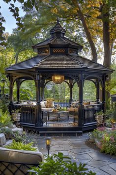 a gazebo sitting in the middle of a garden surrounded by trees and bushes with chairs around it