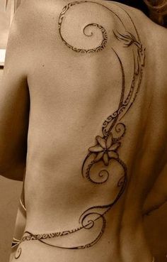 the back of a woman's body with an intricate tattoo on her left side