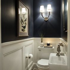 a white toilet sitting next to a sink in a bathroom under two framed pictures on the wall