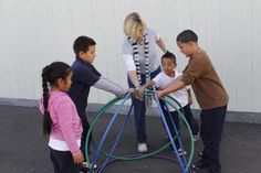 a group of children playing with an object in front of a woman and two boys