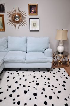 a blue couch sitting on top of a white rug in a living room next to a lamp