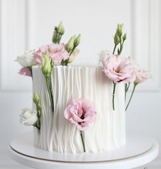 a white cake with pink and white flowers sitting on top of it's icing