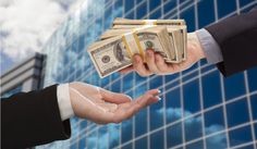 two people shaking hands over money in front of a building with blue sky and clouds